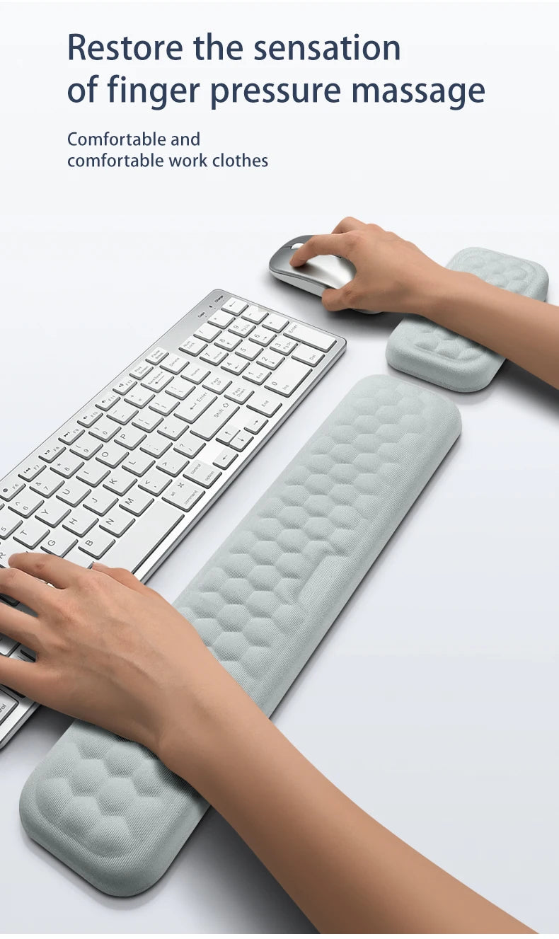 A hand rests on a light gray ergonomic keyboard and mouse with a matching wrist rest pad.