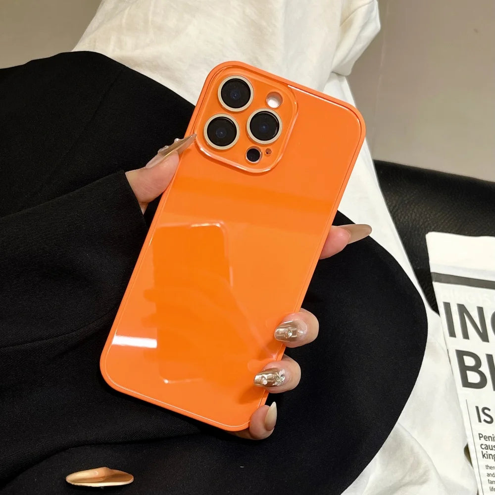 An orange glossy tempered glass shockproof case for an iPhone is being held by a person wearing a black blazer.