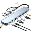 A silver USB hub docking station with multiple ports including USB-C, USB 3.0, and 3.5 audio connectors.
