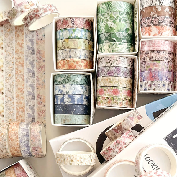A collection of five rolls of floral patterned washi tape in various shades and designs for crafting.