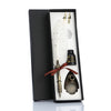 A black gift box containing a feather dip pen set with a decorative knife and a white feather.