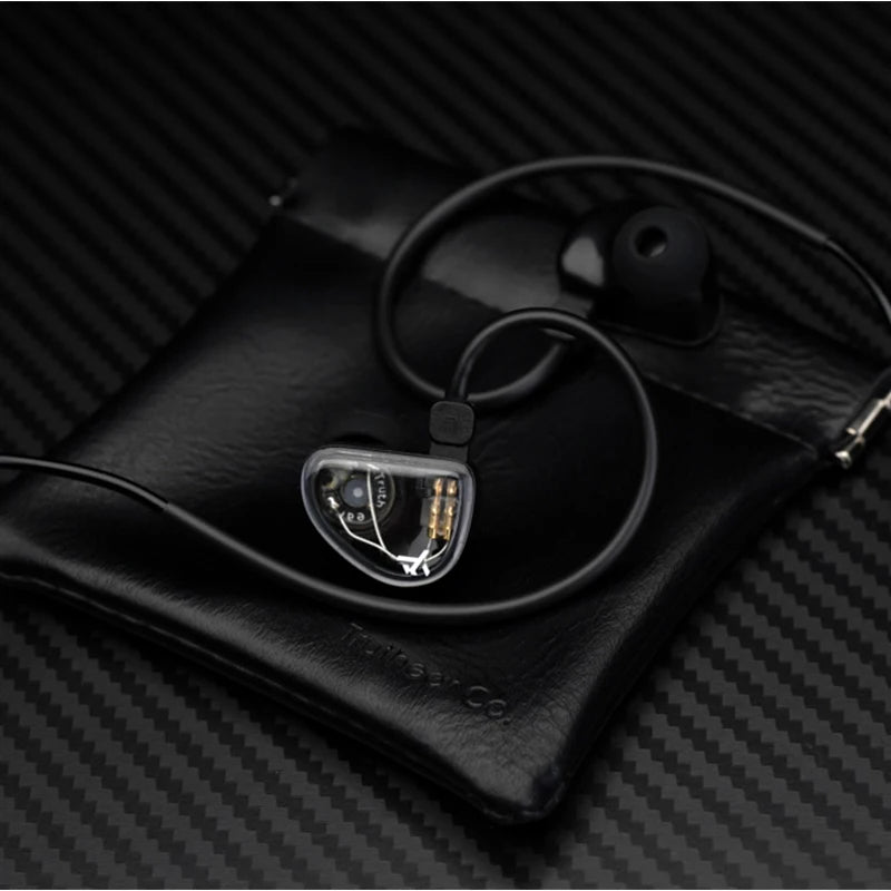 A pair of high-fidelity wired in-ear headphones with a clear housing resting on a black leather case.