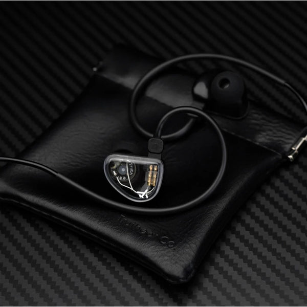 A pair of high-fidelity wired in-ear headphones with a clear housing resting on a black leather case.