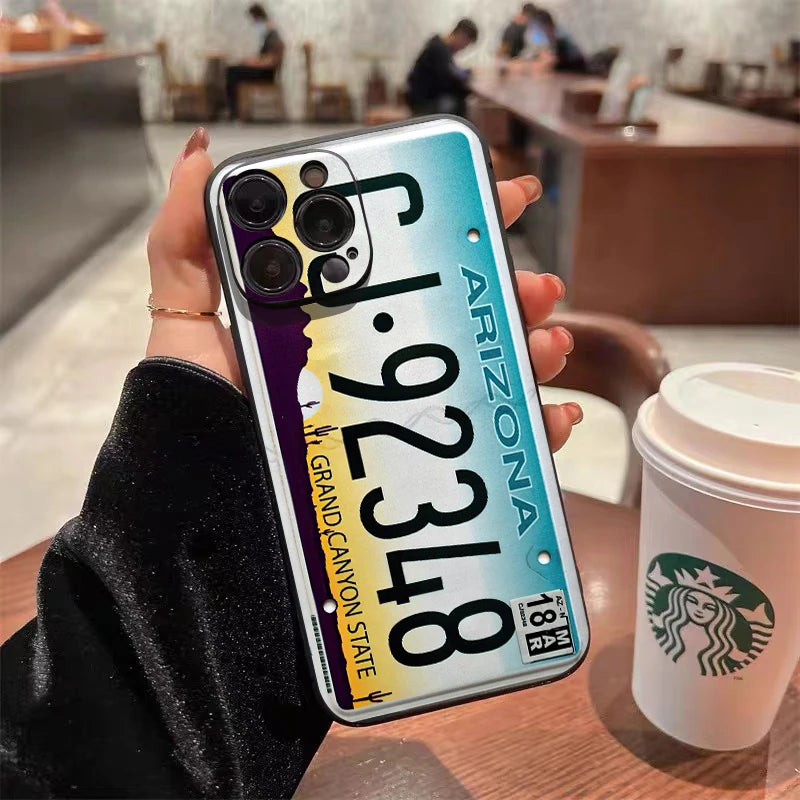 A hand holds a vintage license plate phone case for an iPhone featuring Arizona state details.