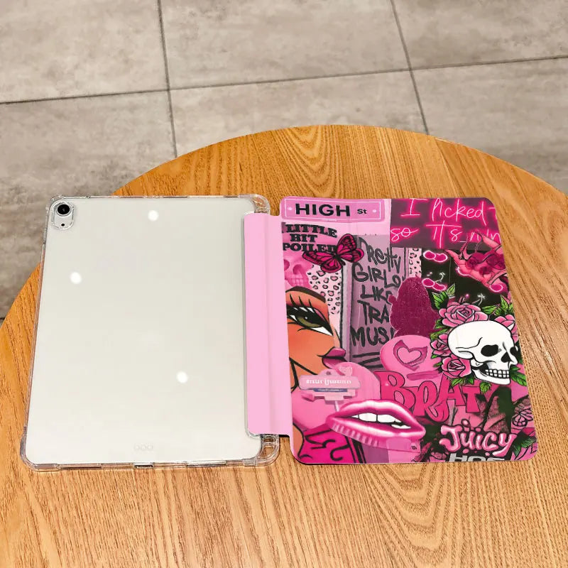 A white tablet case with a pink and black themed cover featuring various graphics and text on a wooden surface.