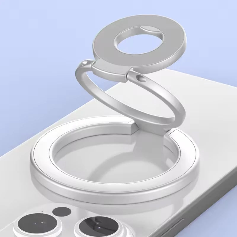 A silver MagSafe double-sided phone ring holder stand resting on a white surface.