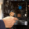 A hand is using an orange electric air duster to clean dust from inside a computer case fan.