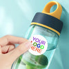 A hand holds a clear water bottle with a yellow cap and a dark blue silicone seal, featuring green fruit slices inside.