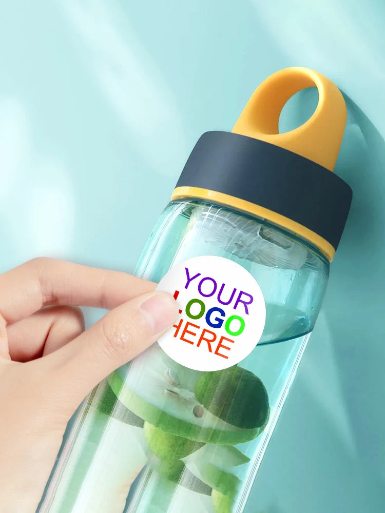 A hand holds a clear water bottle with a yellow cap and a dark blue silicone seal, featuring green fruit slices inside.