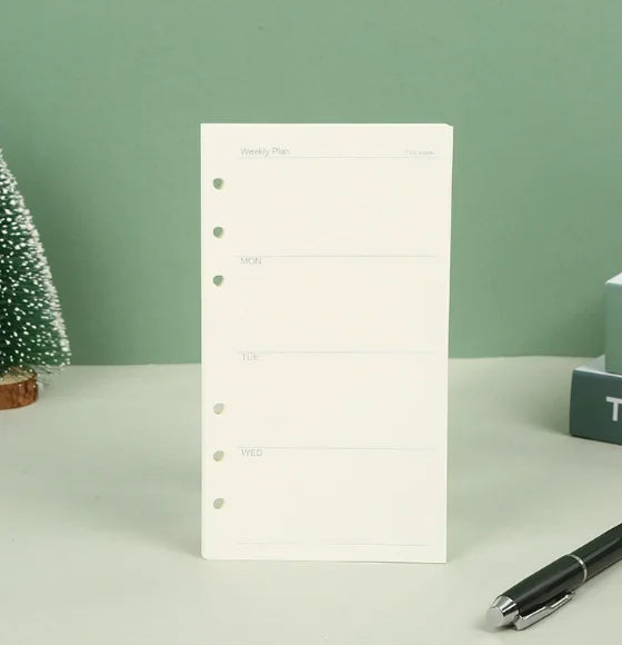 Cuaderno semanal blanco con líneas en blanco para lunes, martes y miércoles, mostrado sobre una superficie clara.