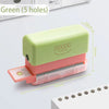A light green mini multi-hole punch with a pink base and a silver punch bar, shown next to paper.