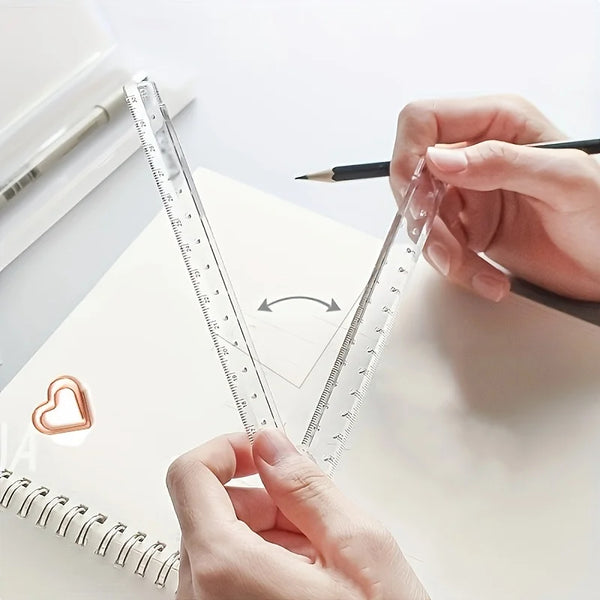 A hand holds a clear acrylic folding ruler against a notebook, demonstrating its measurement scale.