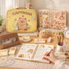 A yellow Capybara pencil case with a bear design, next to a notebook and stationery items.