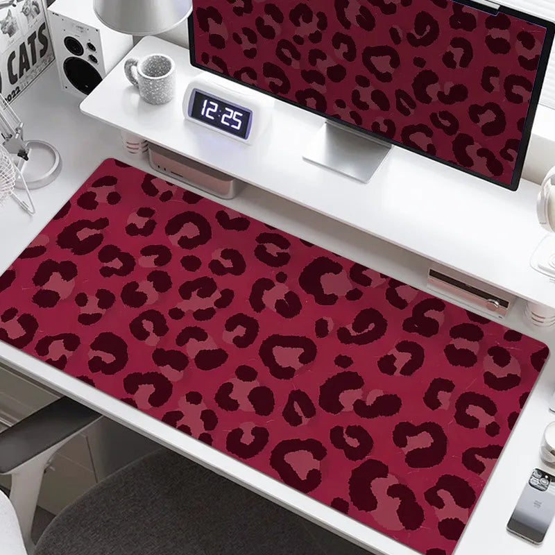 A large desk pad with a leopard print design featuring shades of pink and maroon.