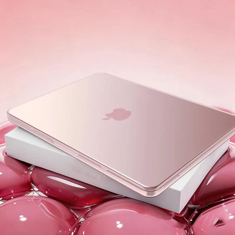 A pink Apple laptop is shown resting on a white protective case surrounded by glossy pink spheres.