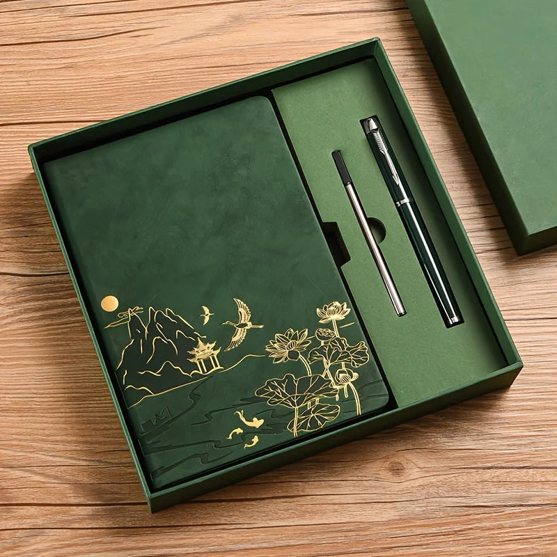 A dark green box containing a luxury notebook set with gold accents and a black pen on a wooden surface.