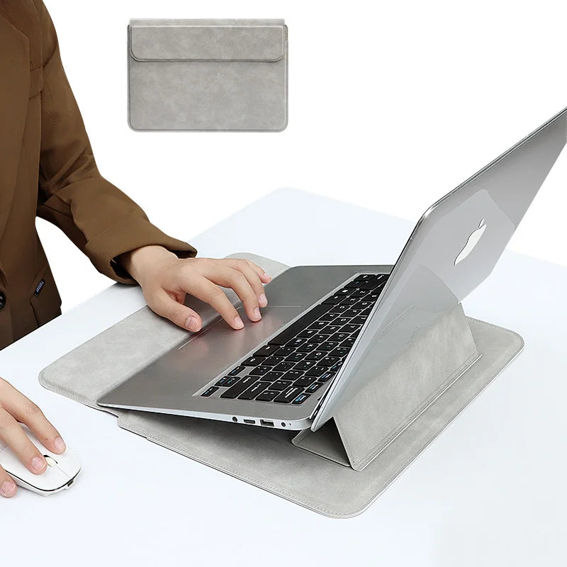 Eine Person legt einen silbernen Laptop in eine graue Kunstlederhülle auf einem weißen Schreibtisch.