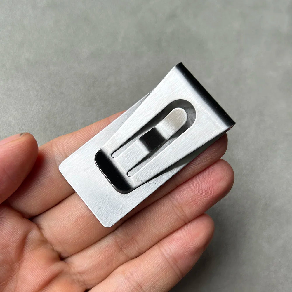 A silver personalized engraved money clip wallet is held in a person's hand.