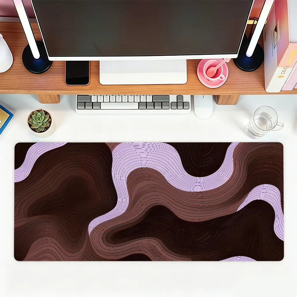 A dark brown and purple abstract wave mouse pad placed on a wooden desk with a laptop and peripherals.
