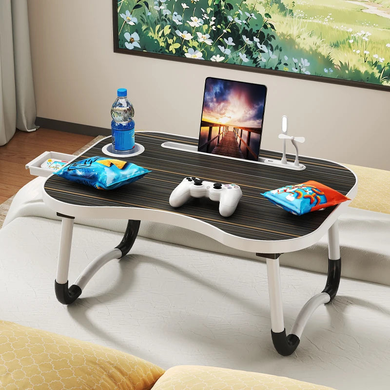 A multi-functional laptop desk organizer tray holding a laptop, a bottle of water, and colorful cushions on a wooden surface.