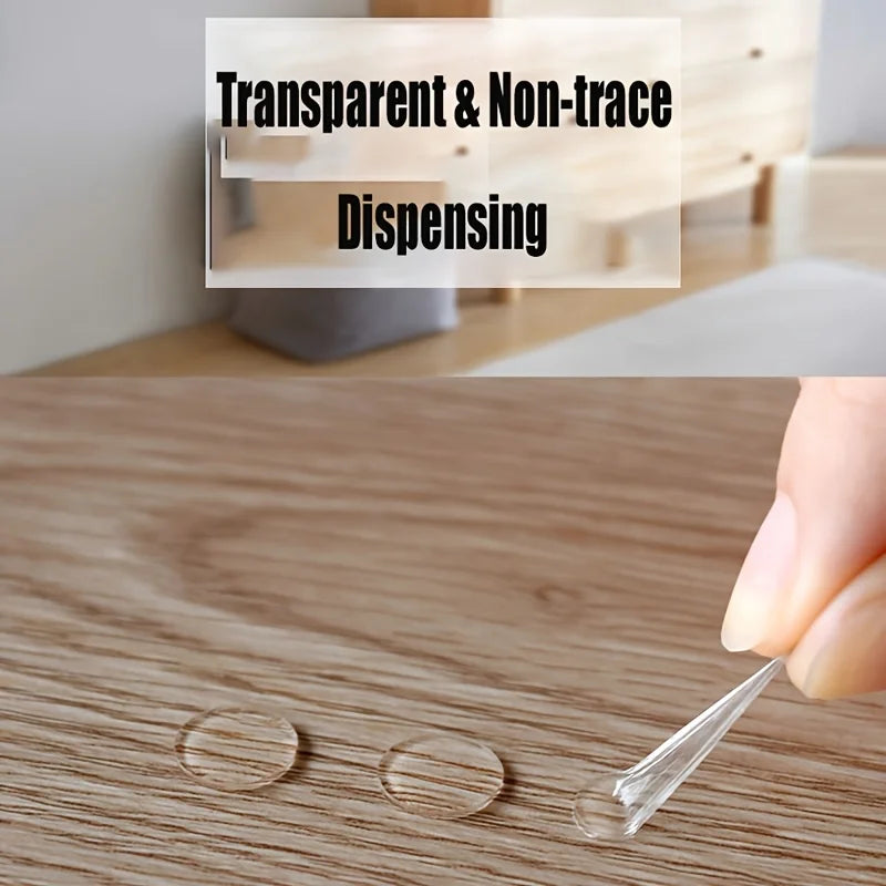 Une main applique un point de décoration adhésif double face transparent sur une surface en bois.