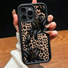 A hand holds a black leopard print phone case featuring a black floral design for an iPhone.
