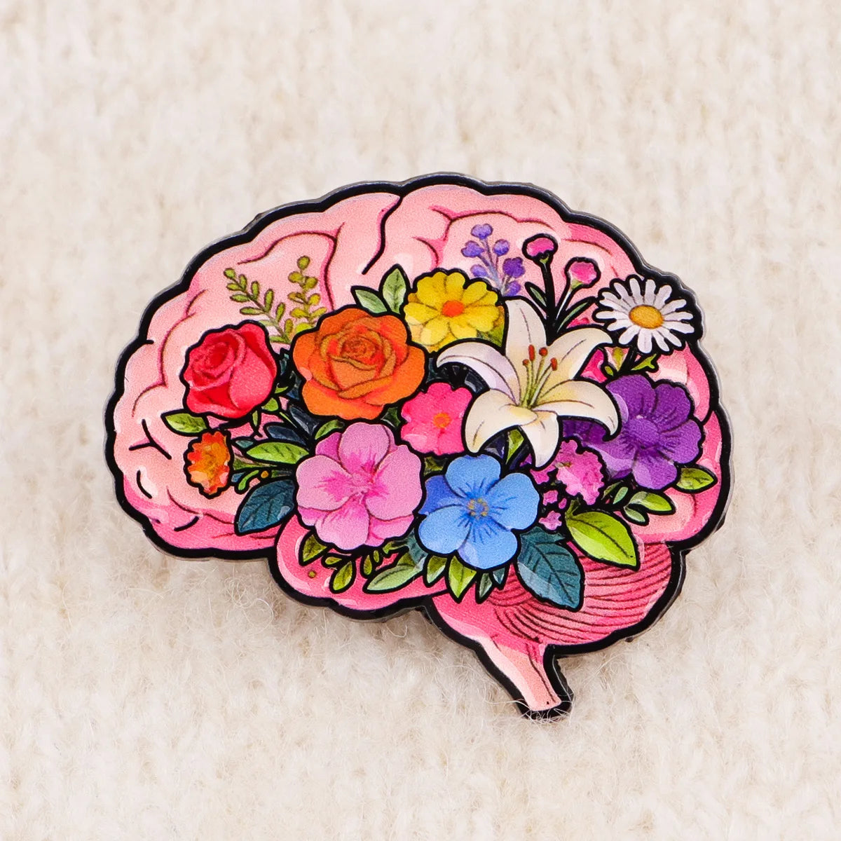 Enamel pin shaped like a pink brain filled with colorful flowers and leaves