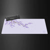A light purple gaming mouse pad featuring a delicate branch of cherry blossoms and small pink flowers.