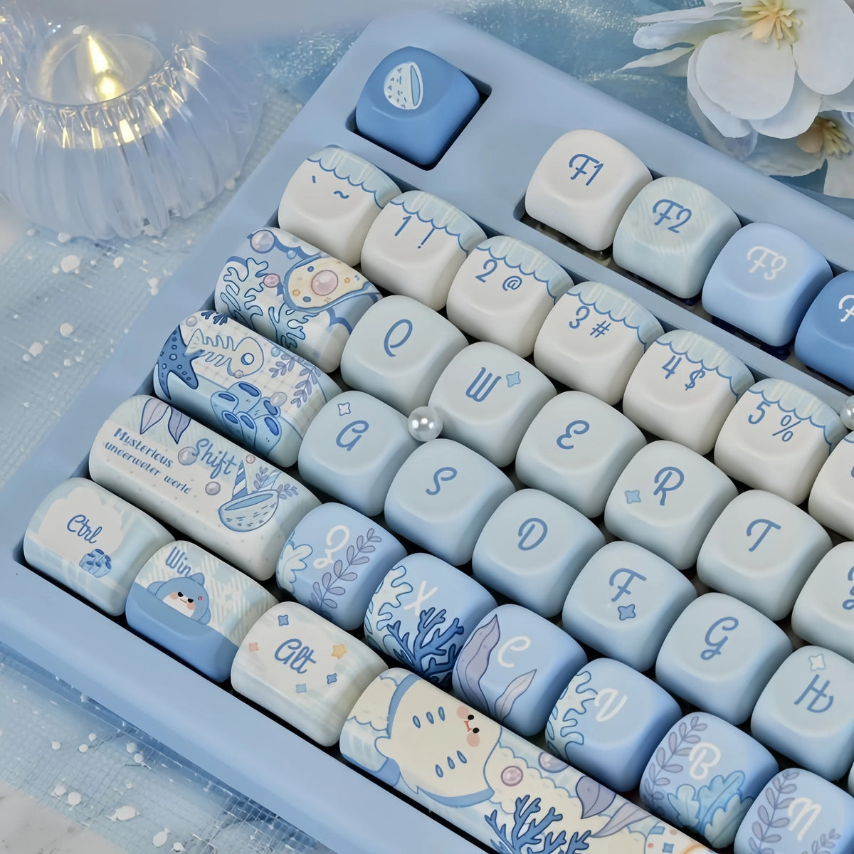 A close-up view of light blue and white PBT keycaps featuring a sea theme used for a mechanical keyboard