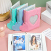 A pink hollow photo card binder with a heart design and a set of matching blue and teal binders.