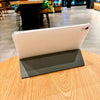 A white tablet case with a clear protective cover is displayed on a wooden table.