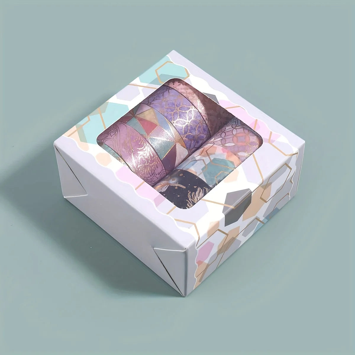 A square box containing a set of metallic gold washi tape rolls with iridescent purple and pink tones.