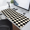 A black and white checkered desk mat is placed on a white desk next to a computer monitor.