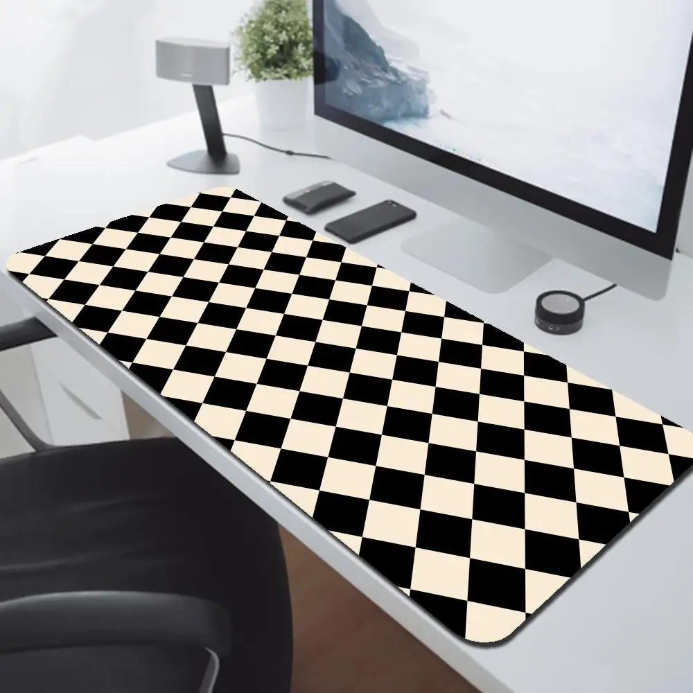 A black and white checkered desk mat is placed on a white desk next to a computer monitor.