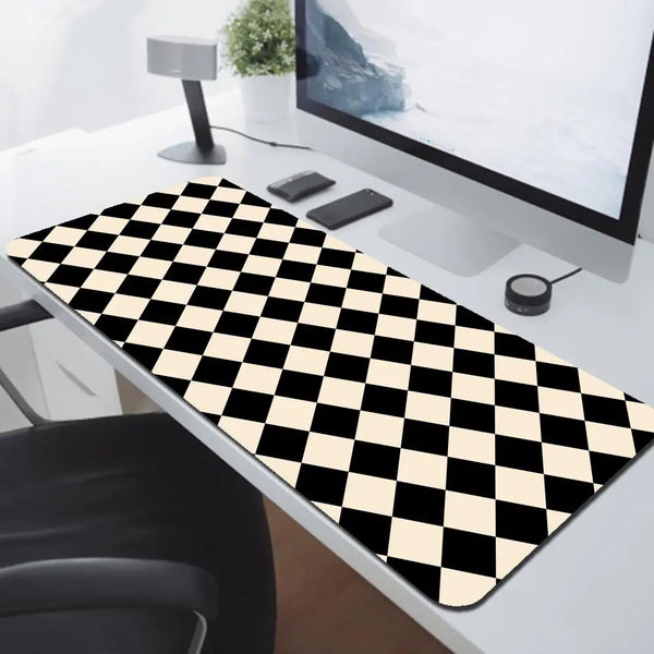 A black and white checkered desk mat is placed on a white desk next to a computer monitor.