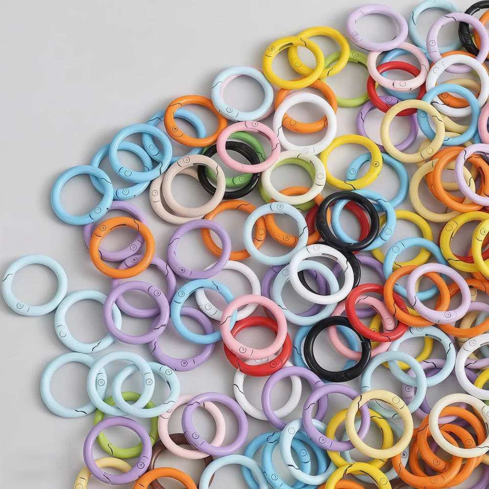 A collection of colorful spring clasps in various colors like yellow, orange, pink, and blue arranged on a light gray surface