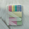 A stack of A6 sticky note notebook featuring colorful stickers and a white page on a white fluffy surface.