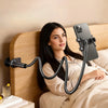 A woman is holding an adjustable black phone and tablet holder with a flexible neck, resting on a wooden surface.