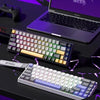 A purple laptop is shown with a wired compact gaming keyboard and a separate mechanical keyboard on a dark surface.