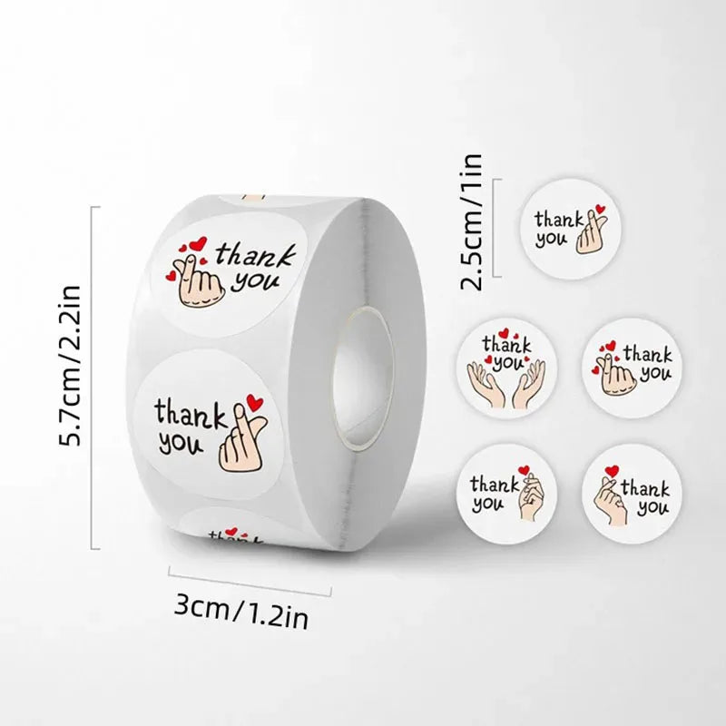 A roll of thank you stickers with various hand gestures and red hearts, shown next to a ruler for scale.