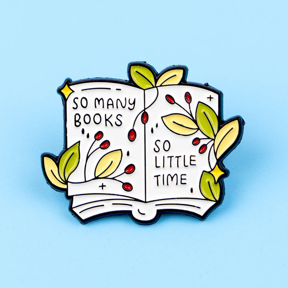 An enamel lapel pin shaped like an open book with leaves and text reading So many books so little time