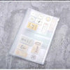 Bolsa de cierre plástico transparente llena de varias etiquetas e artículos pequeños sobre una superficie gris texturizada.