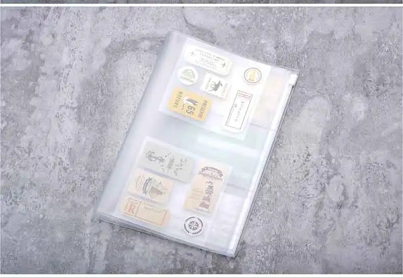 Bolsa de cierre plástico transparente llena de varias etiquetas e artículos pequeños sobre una superficie gris texturizada.