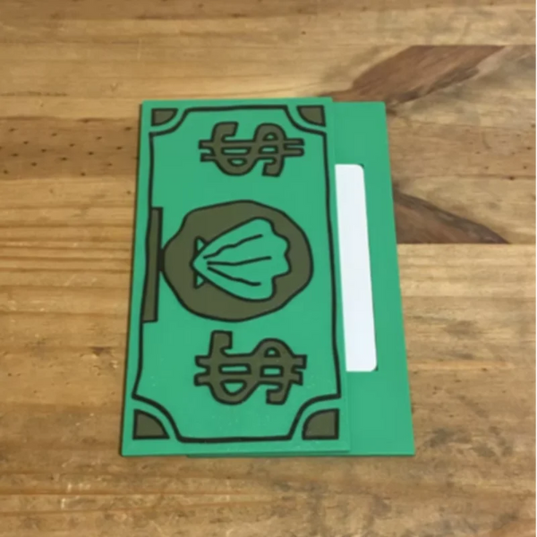 A green card holder with a design featuring a shell and dollar sign symbol on a wooden surface.
