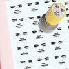 A yellow rubber stamp with a funny meme face design is shown stamping a sheet of paper with multiple faces.