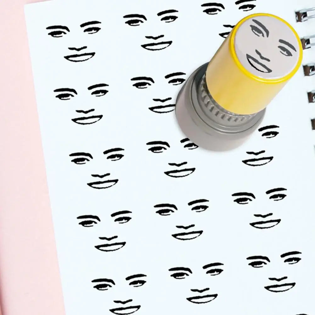A yellow rubber stamp with a funny meme face design is shown stamping a sheet of paper with multiple faces.