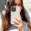 A woman holds a pink and white striped magnetic dual-layer phone case for an iPhone.