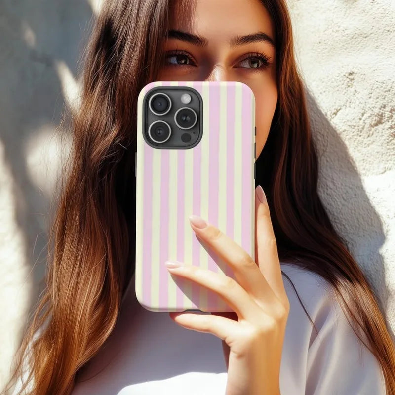 A woman holds a pink and white striped magnetic dual-layer phone case for an iPhone.