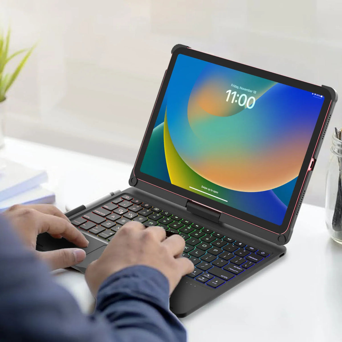 Eine Person benutzt eine beleuchtete Tastatur-Hülle mit Trackpad für ein iPad auf einer weißen Oberfläche.