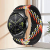 A black smartwatch with a woven multi-colored nylon strap is displayed against a light background.